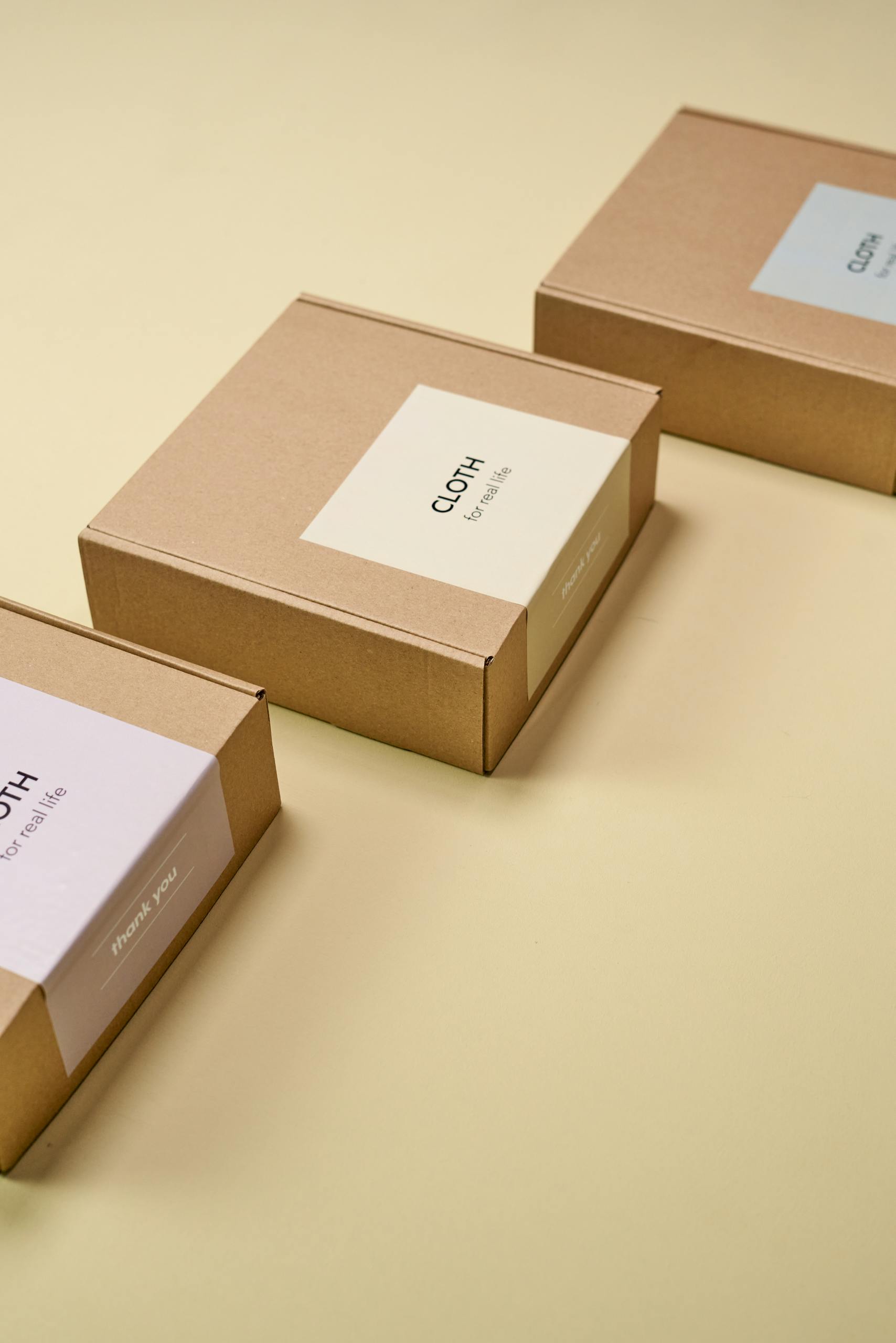 Three cardboard boxes arranged on a yellow surface, showcasing minimalist design for packaging.